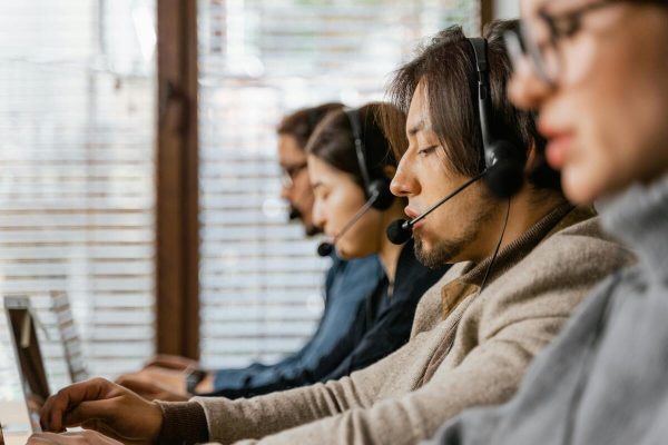 Customer service agents taking phone calls in an office, representing live chat vs phone support strategies for businesses.